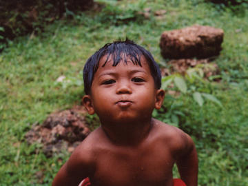 Image of young boy in forest spitting water at the camera