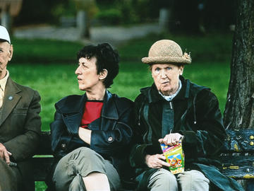 Image of woman and two man sitting in a green park