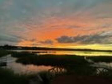 A tricolour sky - blue, neon orange, and yellow - reflect off the water below. 