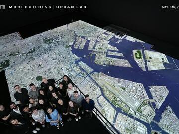 Group photo of students looking at large-scale rendering of Tokyo