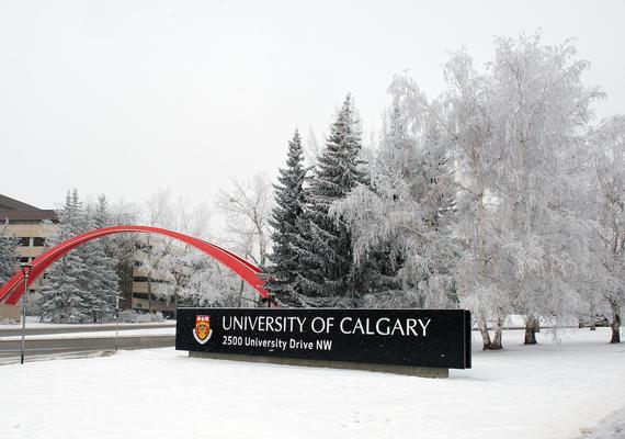 Image of campus entry road in winter with snow on the UCalgary welcome sign