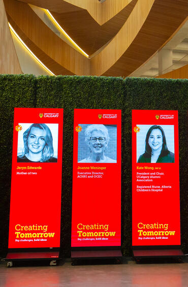Six tall vertical screens introducing event speakers