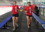 Two athletes jogging forward near a hockey rink