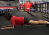 Athlete performing a front plank exercise in an ice hockey arena