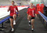 Two athletes performing high knees exercise near a hockey rink
