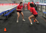 Athletes performing a partner mirroring exercise in an ice hockey arena
