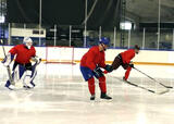 Hockey players performing short single-leg glides with stops across a hockey rink