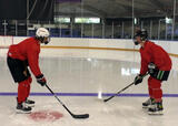 Hockey players performing a partner vestibulo-ocular reflext exercise on a hockey rink