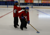 Ringette player stick handling in a ringette stance while partner provides light taps to the head