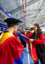 A student is helped into his PhD hood