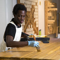 A student paints a wooden board.
