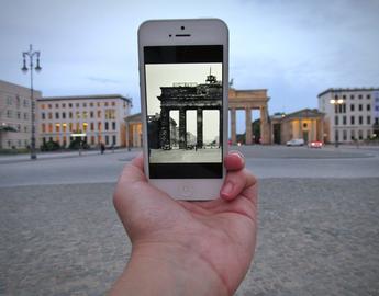 Image of student holding a picture on their phone of 1924 German architecture beside the same building in modern Berlin