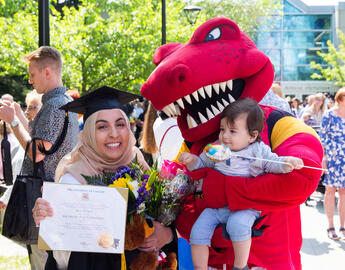 Woman holding her degree with Rex and her baby 