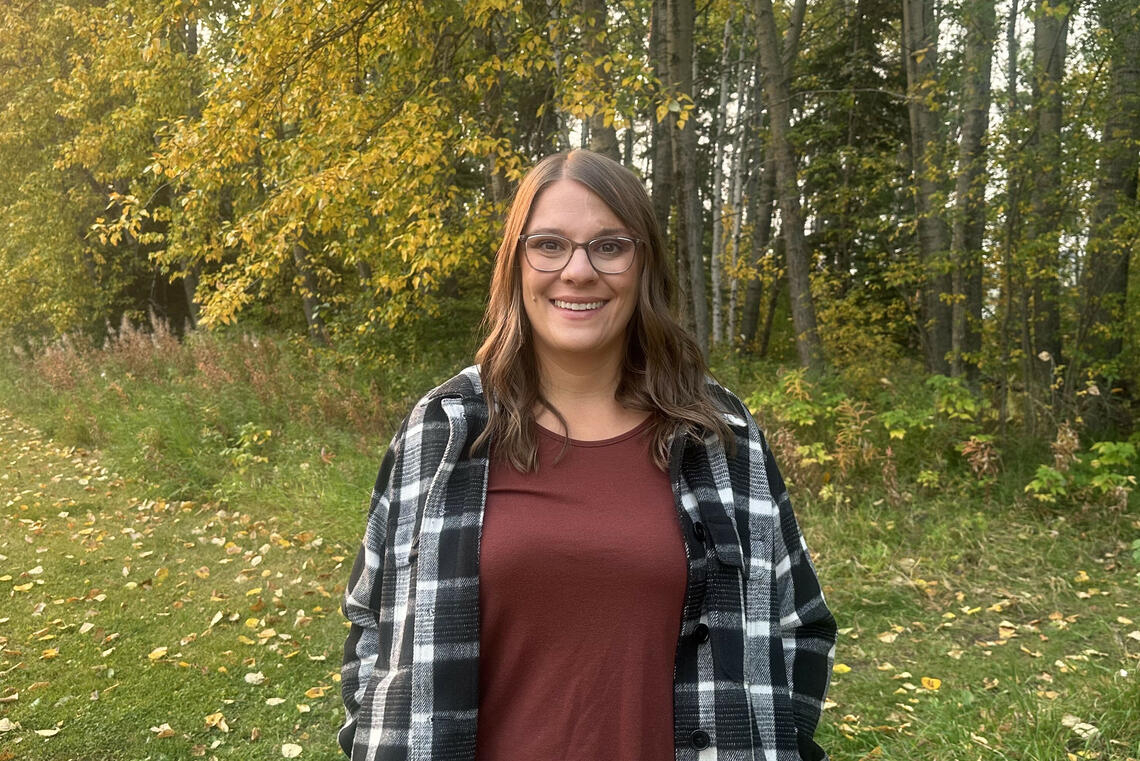 Athena Williams stand surrounded by trees, smiling at the camera