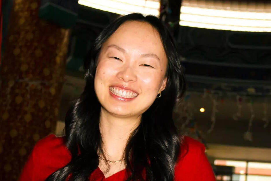 A woman wearing a red shirt smiles at the camera