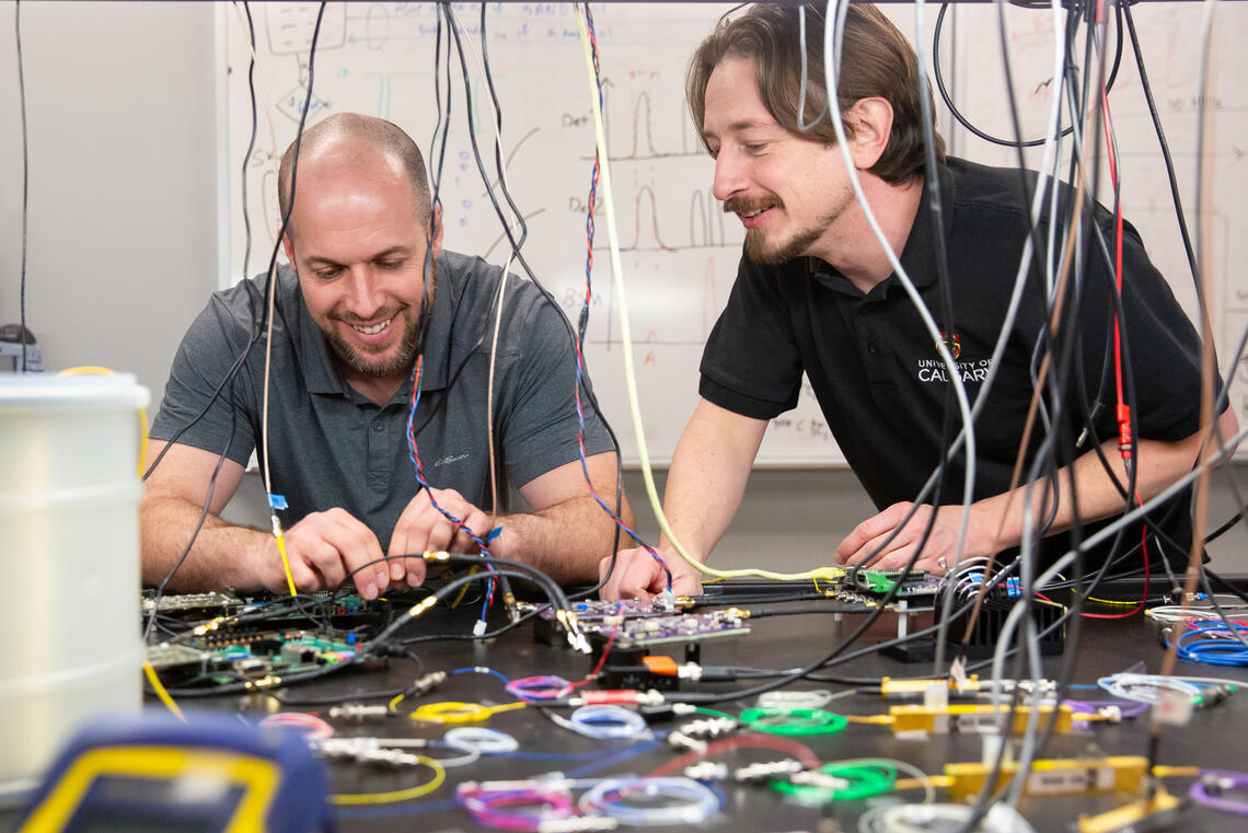 Two men work in a lab surrounded by colourful wires