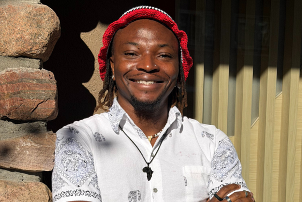 A man wearing a hat smiles at the camera