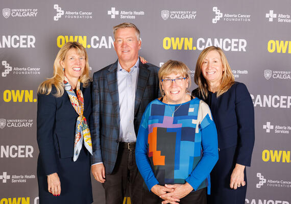 Riddell family stand together in front of a background with the repeated OWN.CANCER logo